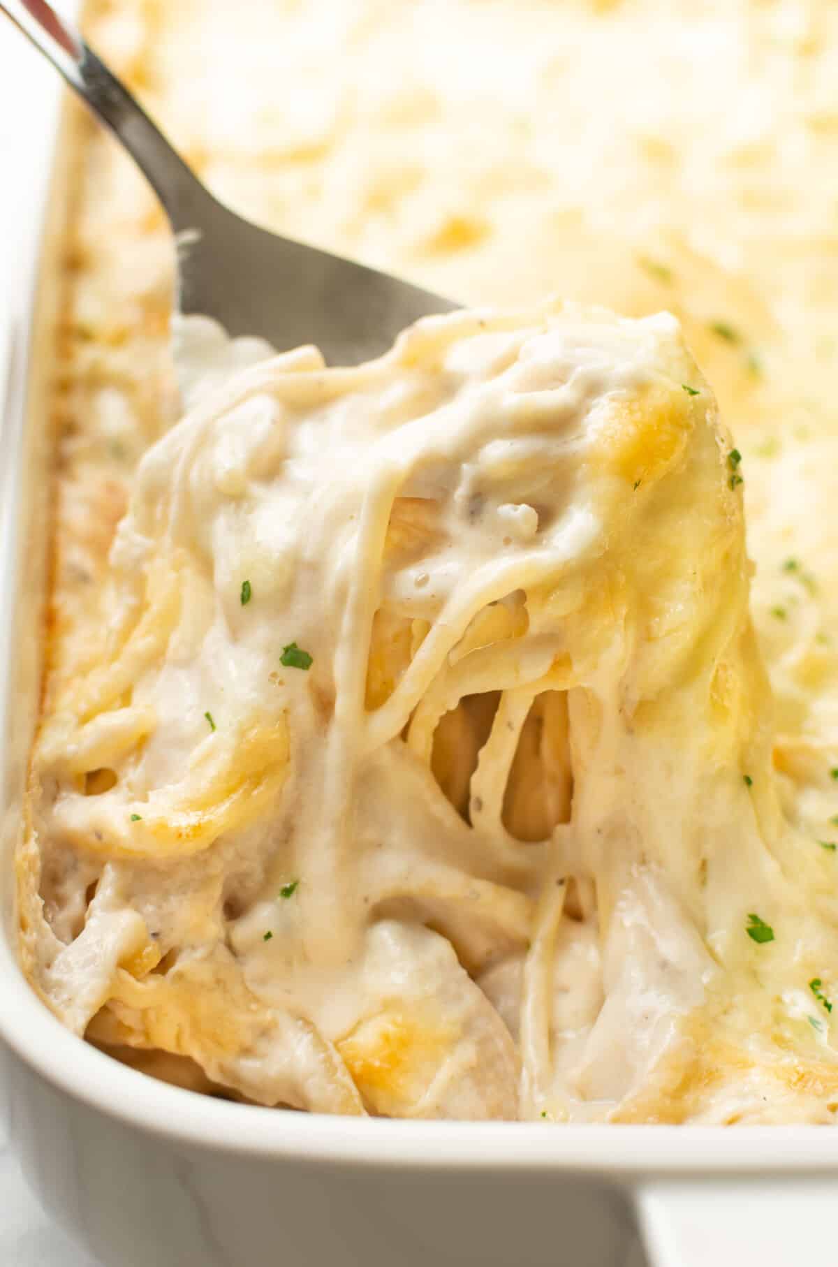 closeup of a baking dish with turkey tetrazzini and a serving spoon