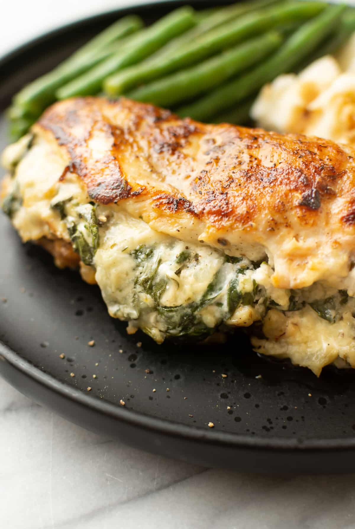 a plate with green beans, mashed potatoes, and a boursin stuffed chicken breast