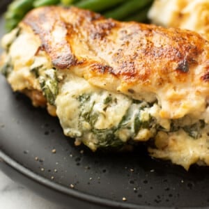 a plate with green beans, mashed potatoes, and a boursin stuffed chicken breast