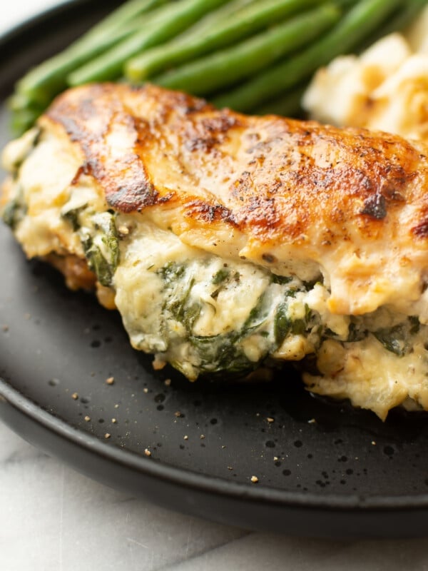 a plate with green beans, mashed potatoes, and a boursin stuffed chicken breast