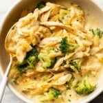 a bowl with cheesy chicken broccoli orzo and a spoon