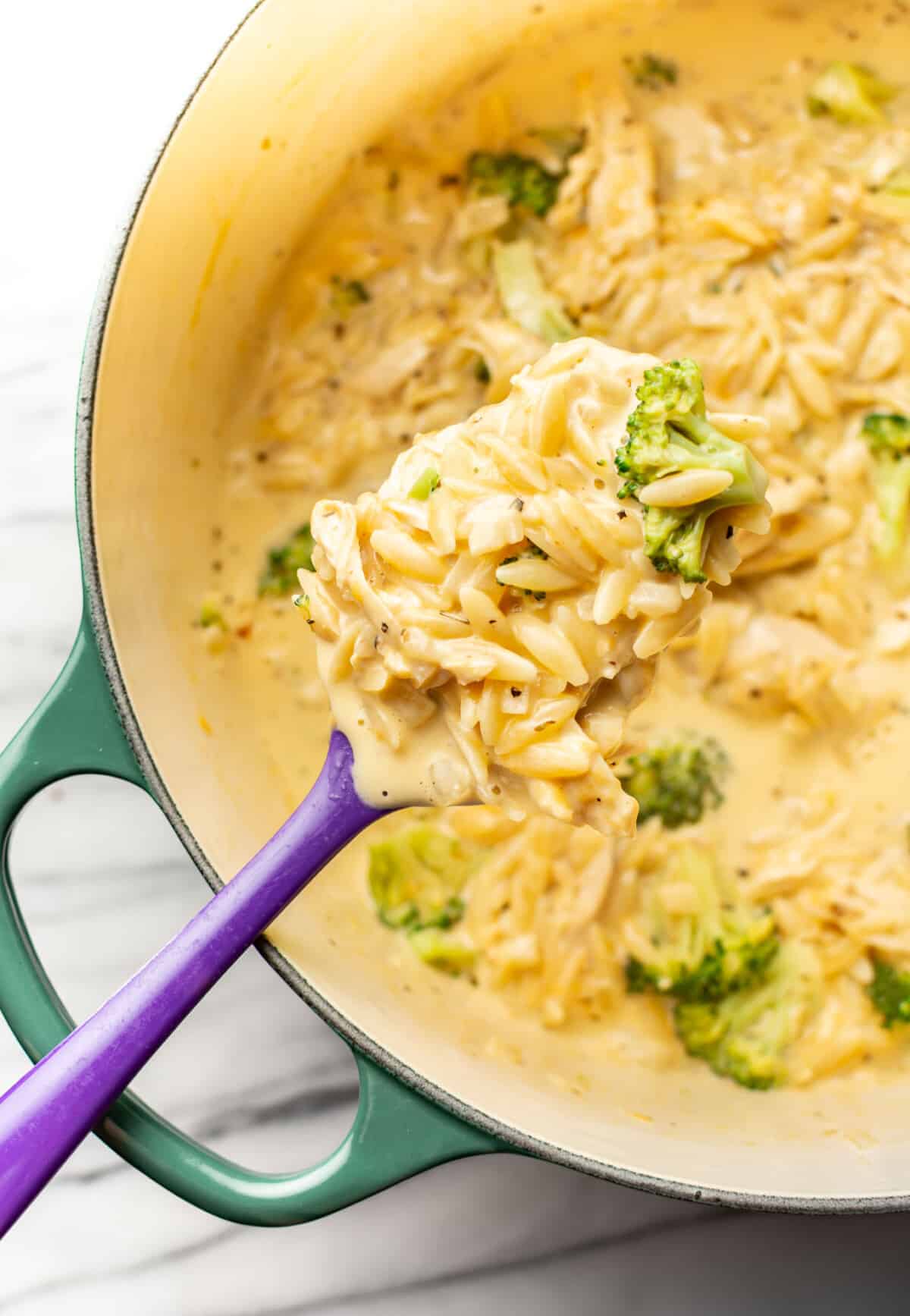 a pot with broccoli cheddar orzo with chicken and a spoon