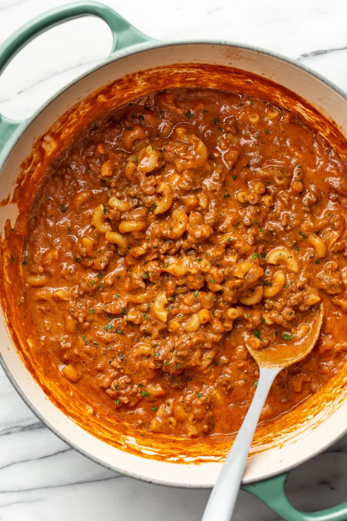 a large pot with chili mac and a serving spoon