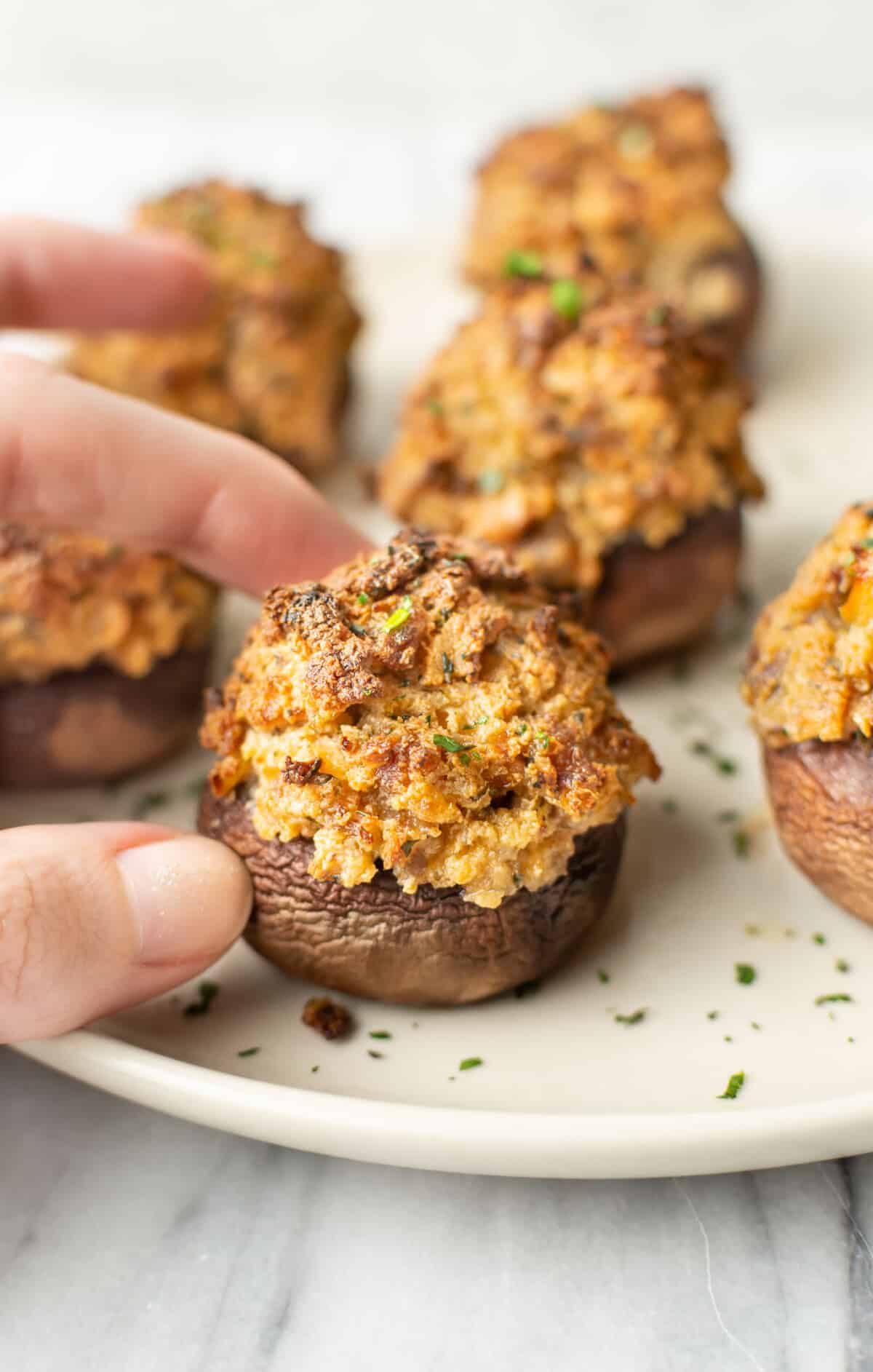 a female hand holding a sausage stuffed mushroom