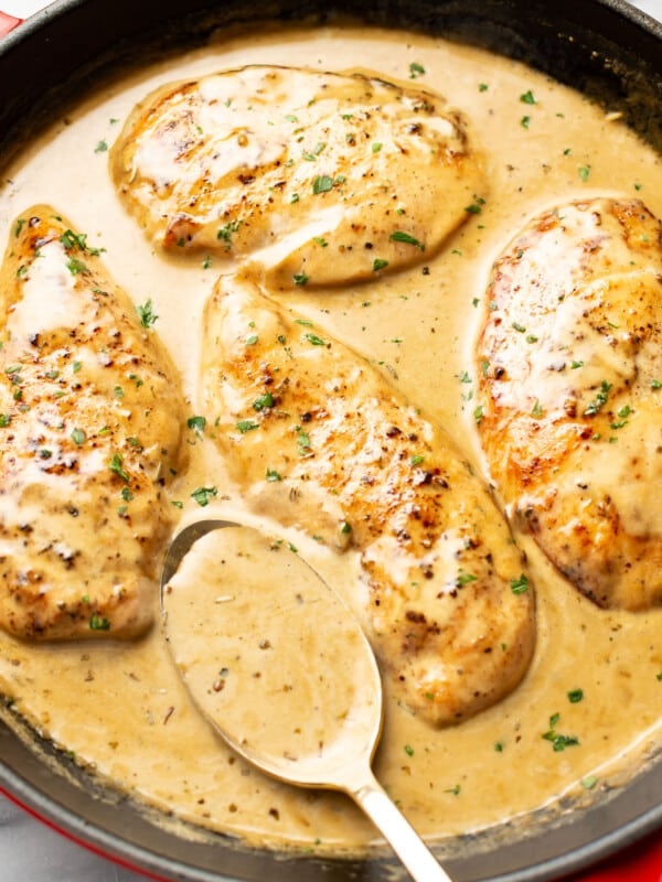 a skillet with creamy maple chicken and a serving spoon