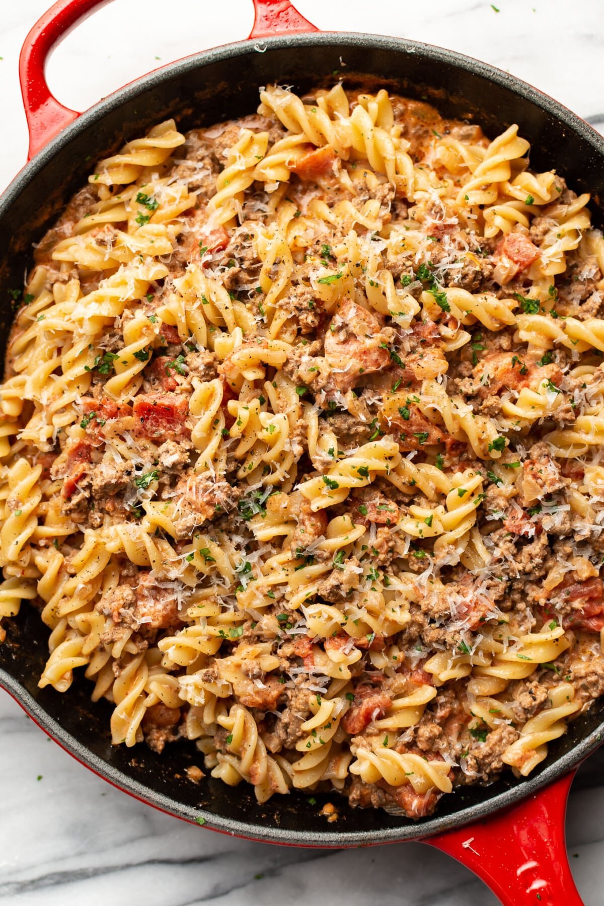 a skillet with creamy ground beef pasta and parmesan