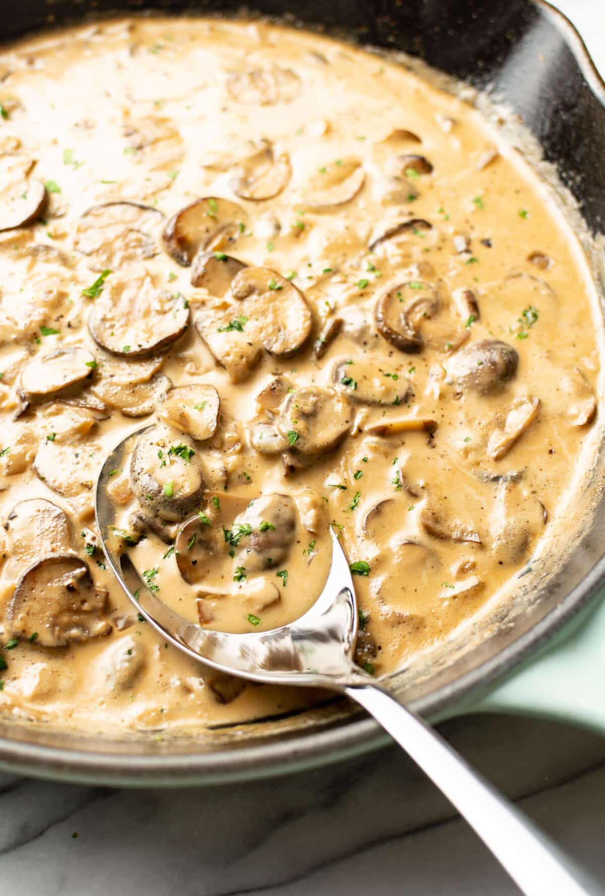 a skillet with marsala wine sauce and a serving spoon