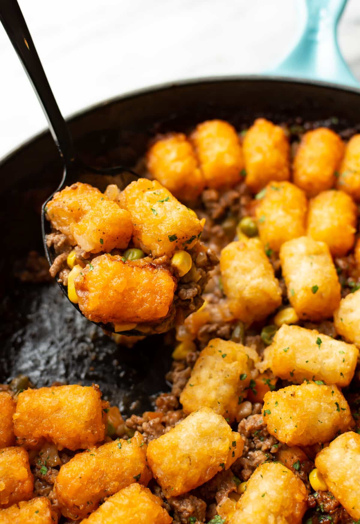 a skillet with tater tot shepherd's pie and a serving spoon