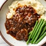 a bowl with red wine braised short ribs, mashed potatoes, and green beans