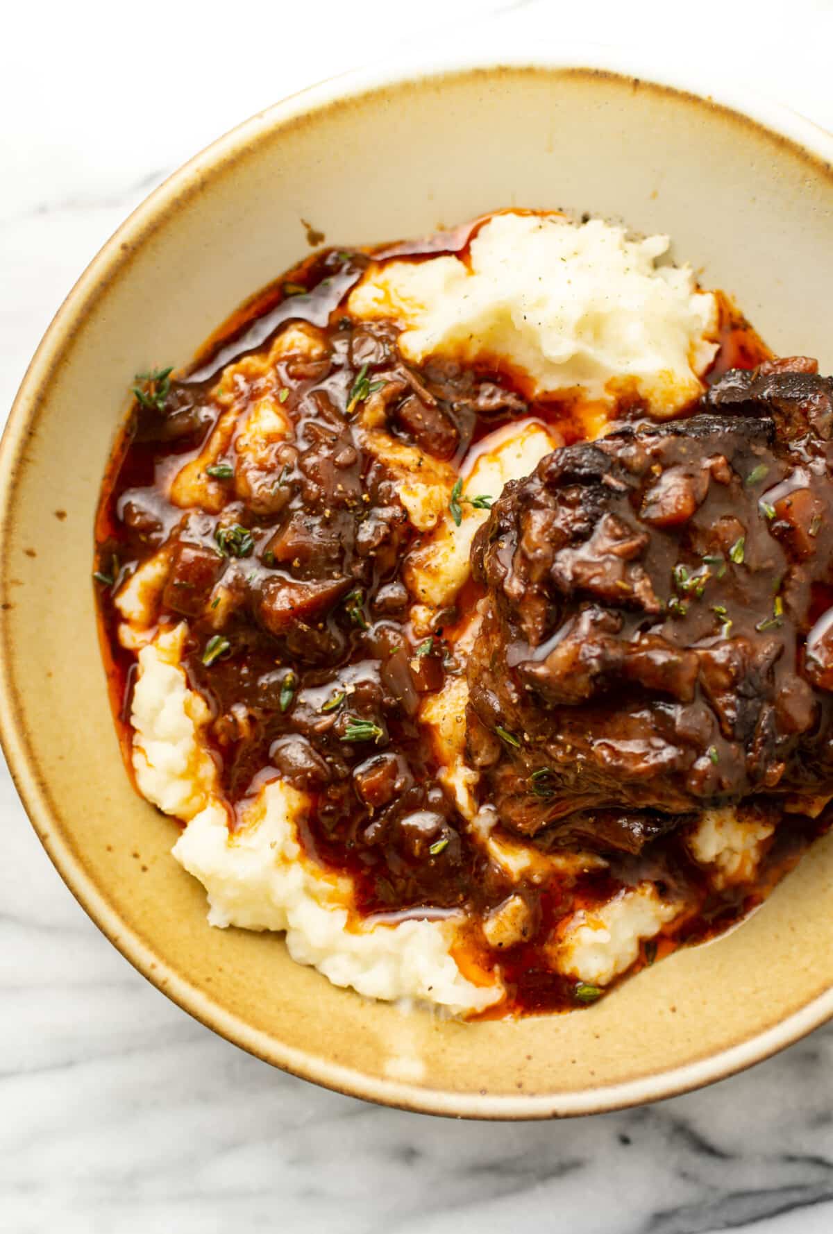 a bowl with red wine braised short ribs over mashed potatoes