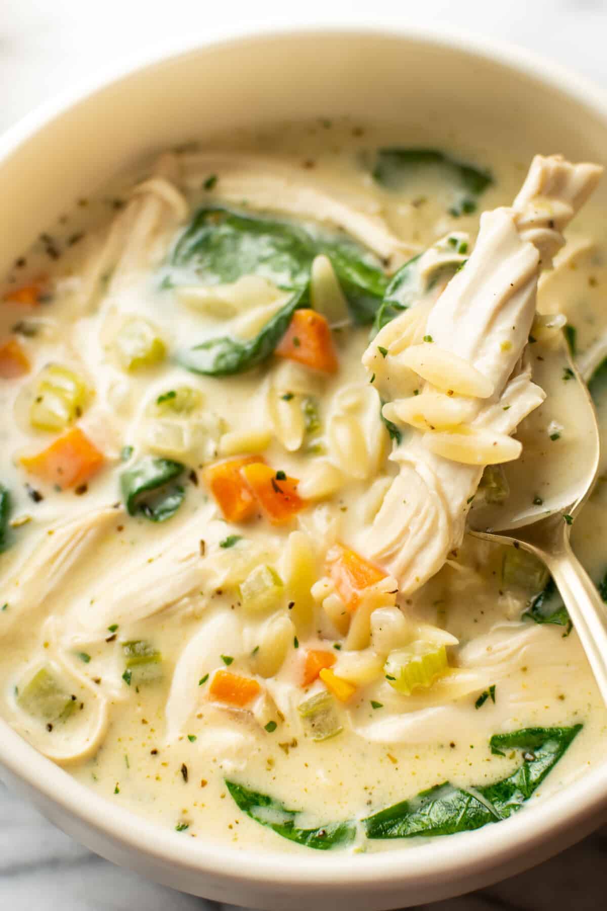 a bowl of creamy lemon chicken orzo soup with a spoon