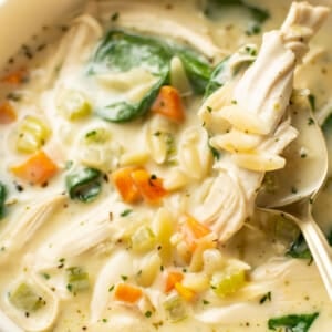 a bowl of creamy lemon chicken orzo soup with a spoon