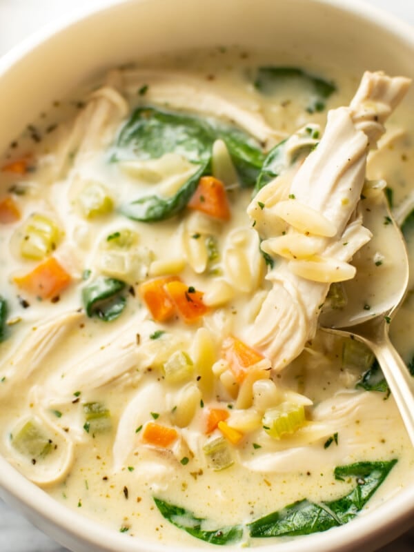 a bowl of creamy lemon chicken orzo soup with a spoon