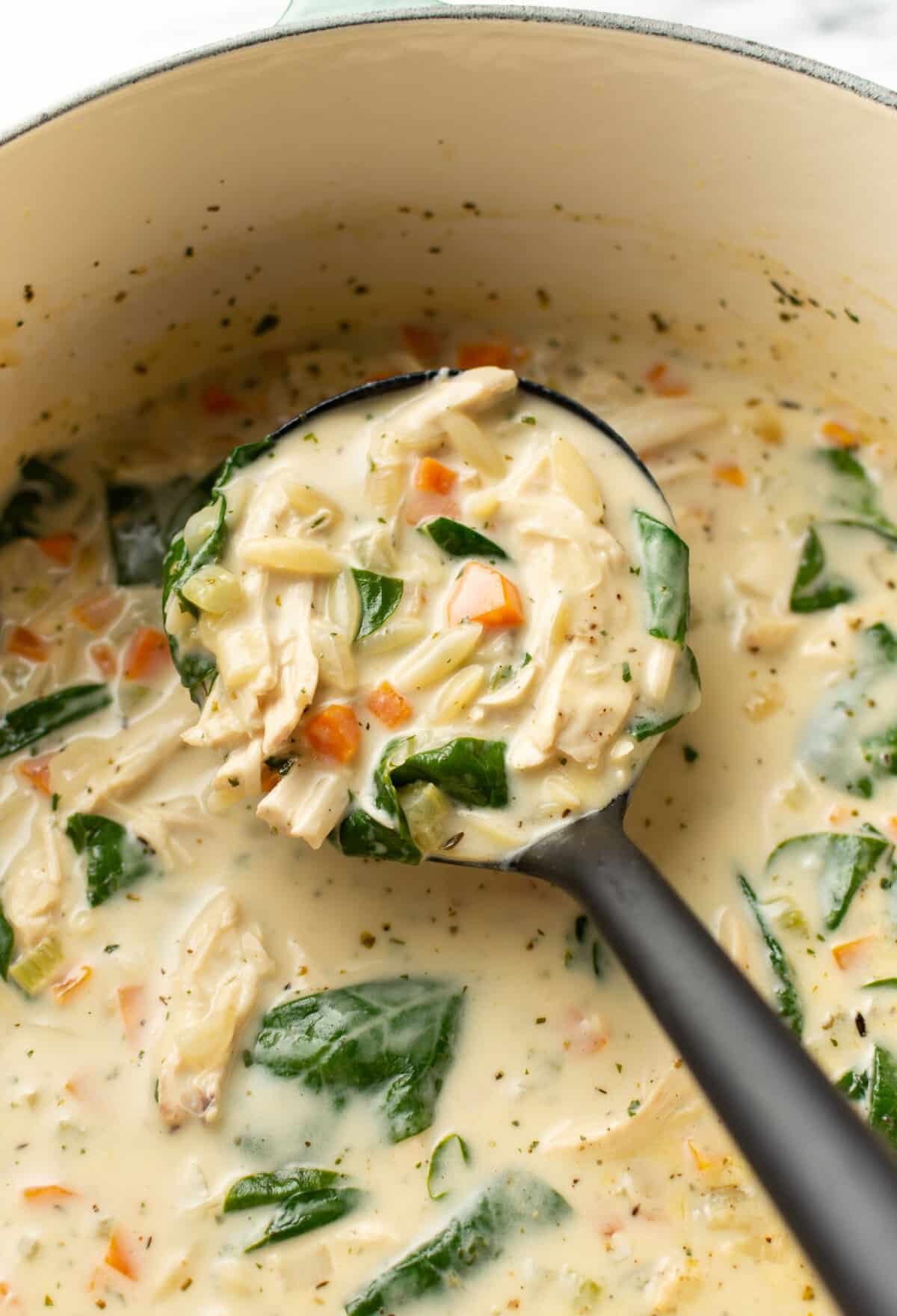 a pot of creamy lemon chicken orzo soup with a ladle