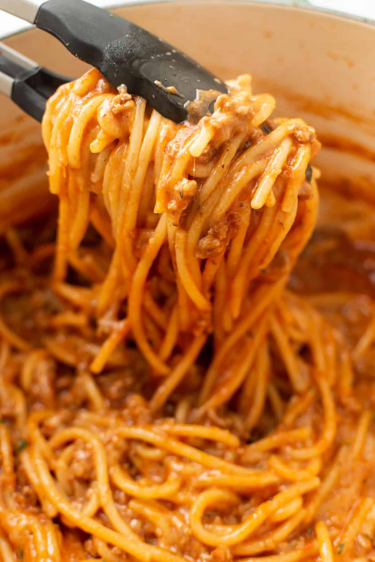 closeup of one pot spaghetti with kitchen tongs