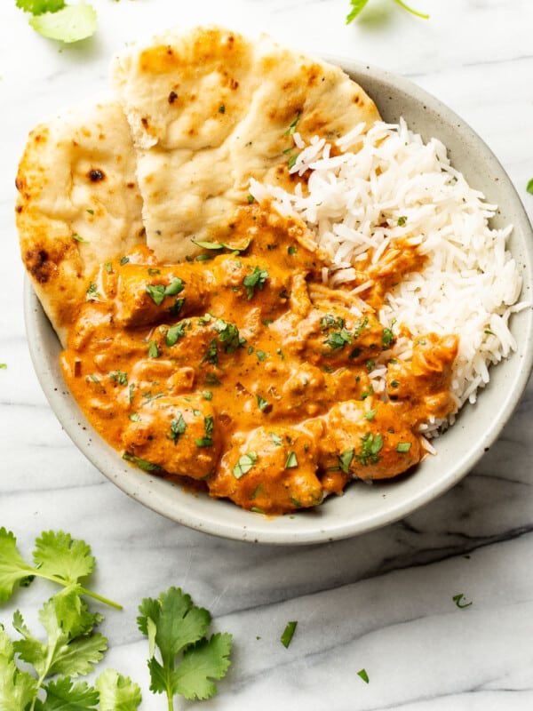 a bowl of butter chicken with basmati rice and naan