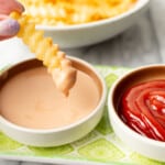 a female hand dipping a french fry into homemade fry sauce