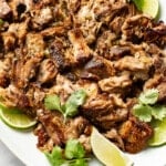 a plate with carnitas and lime wedges