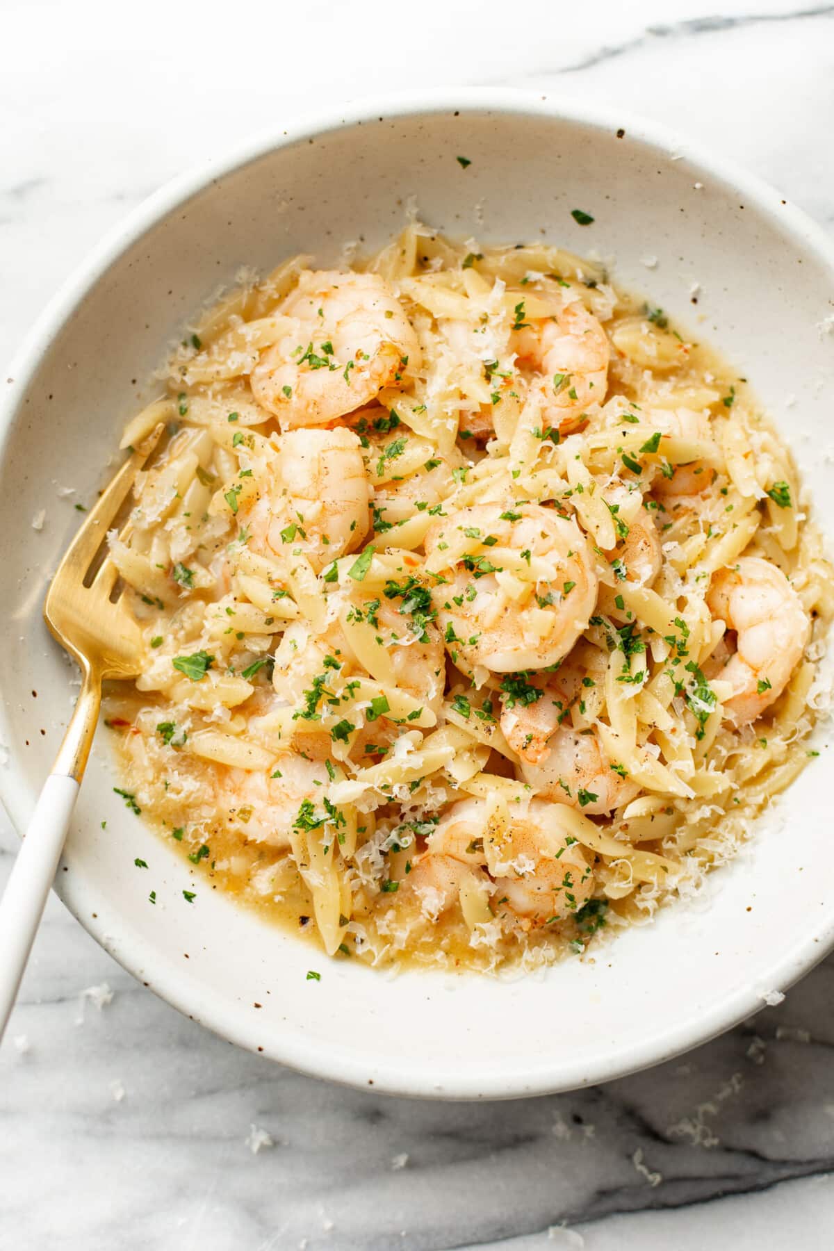 a bowl of shrimp scampi orzo with a fork
