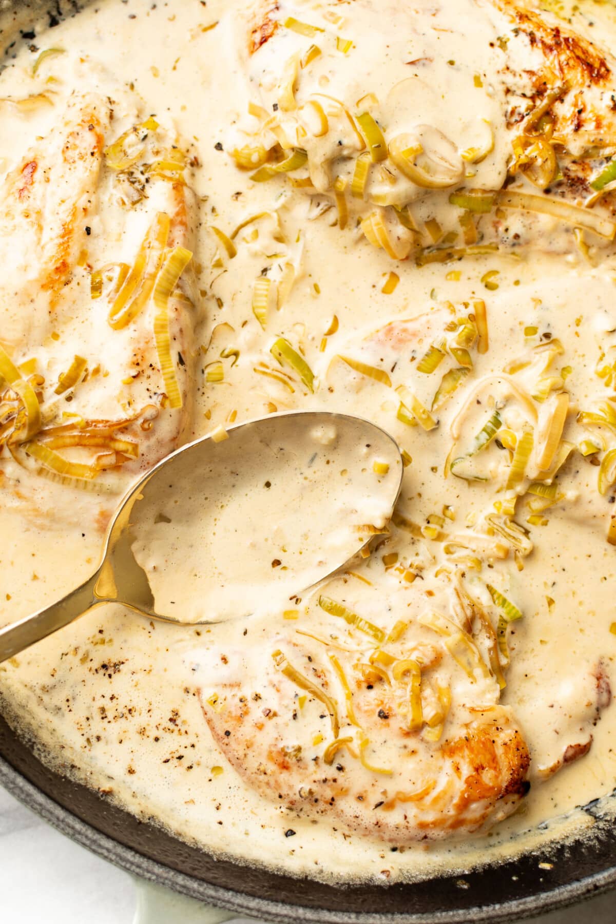 a skillet with creamy leek chicken and a serving spoon