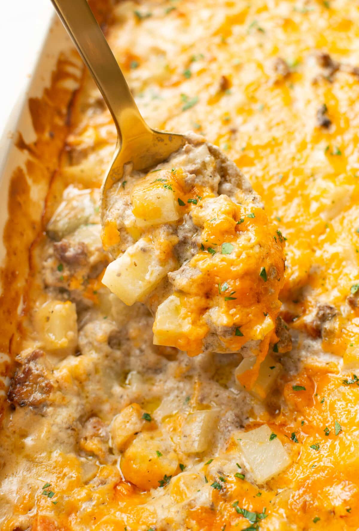 closeup of ground beef and potato casserole with a serving spoon