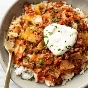 a bowl of unstuffed cabbage rolls over rice with a fork