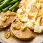 a plate with mississippi pork tenderloin, mashed potatoes, and green beans