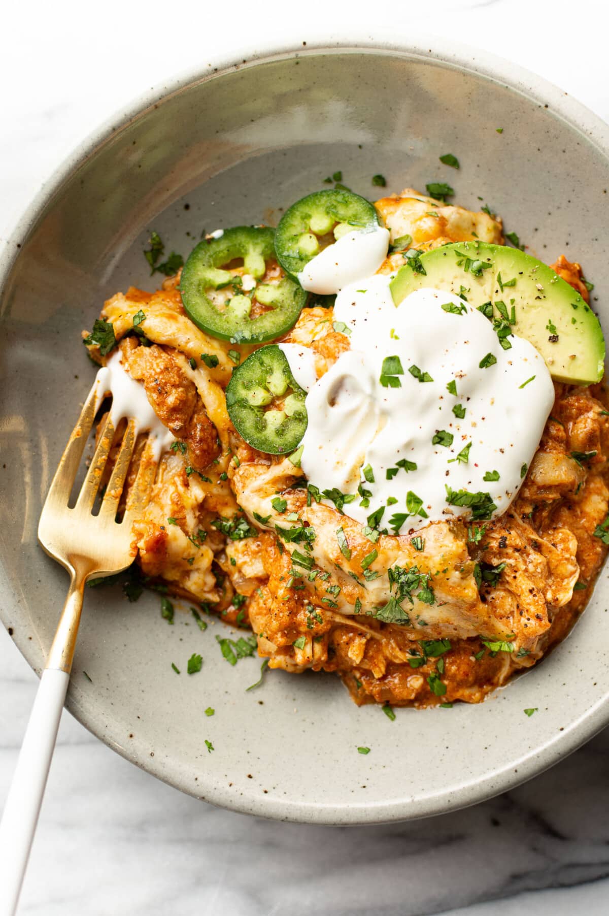 a bowl with a serving of chicken enchilada skillet with a fork