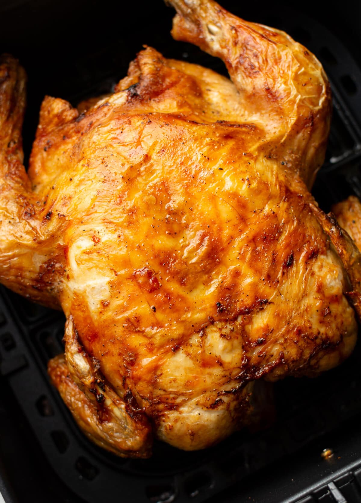a whole roast chicken in an air fryer basket