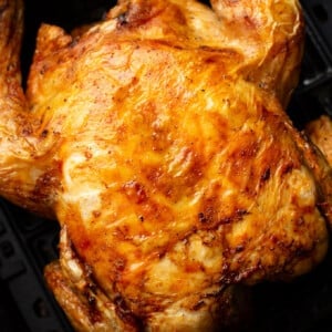 a whole roast chicken in an air fryer basket