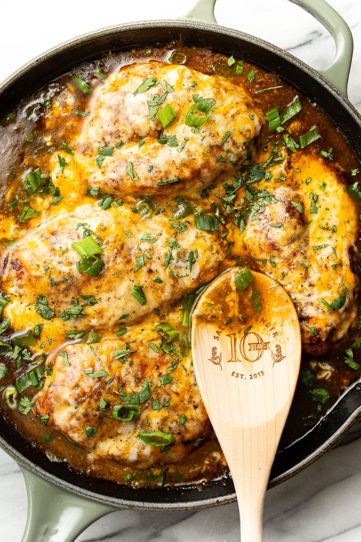 a skillet with green chile chicken and a wooden spoon