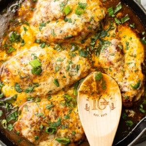 a skillet with green chile chicken and a wooden spoon