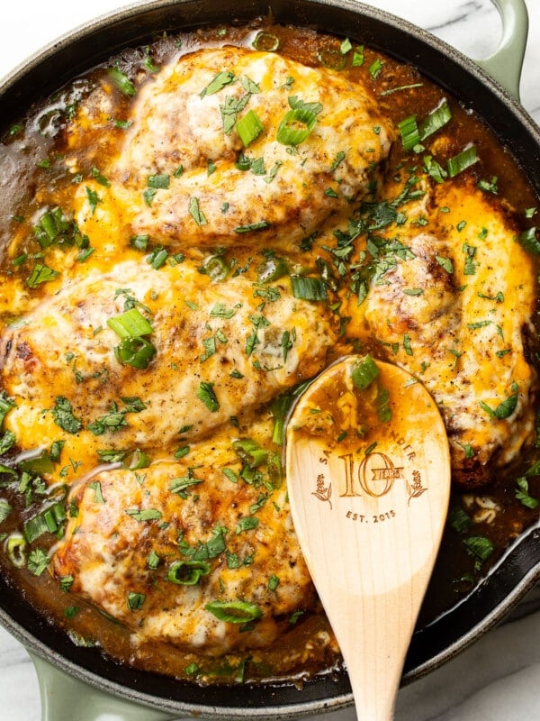 a skillet with green chile chicken and a wooden spoon