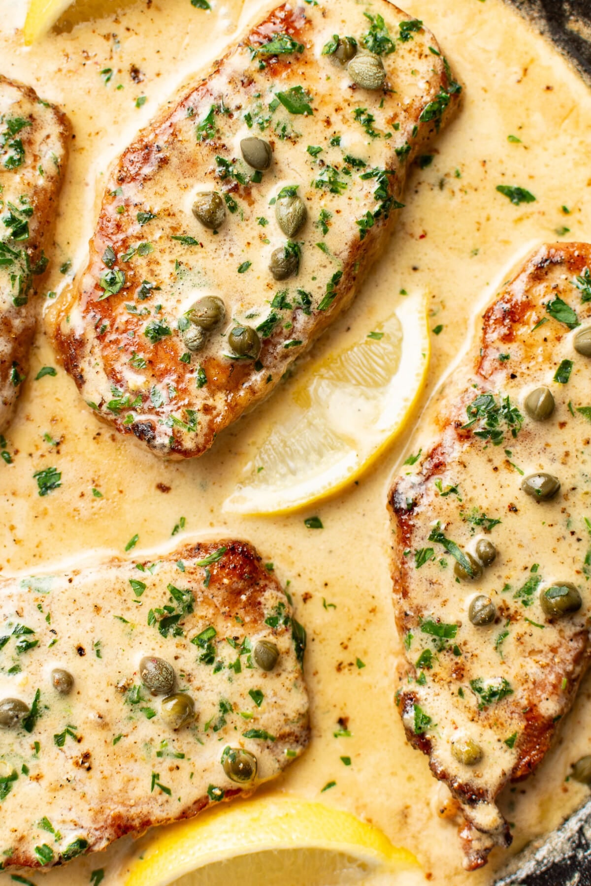 a skillet with pork chops piccata