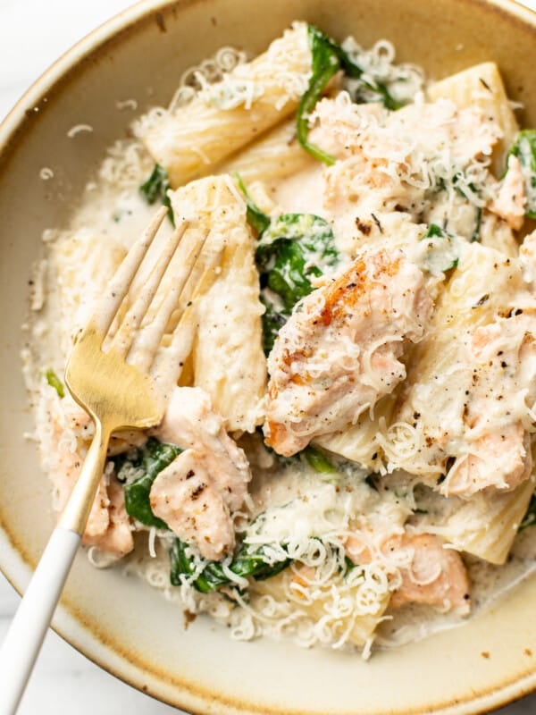 a bowl of lemon spinach salmon pasta with a fork