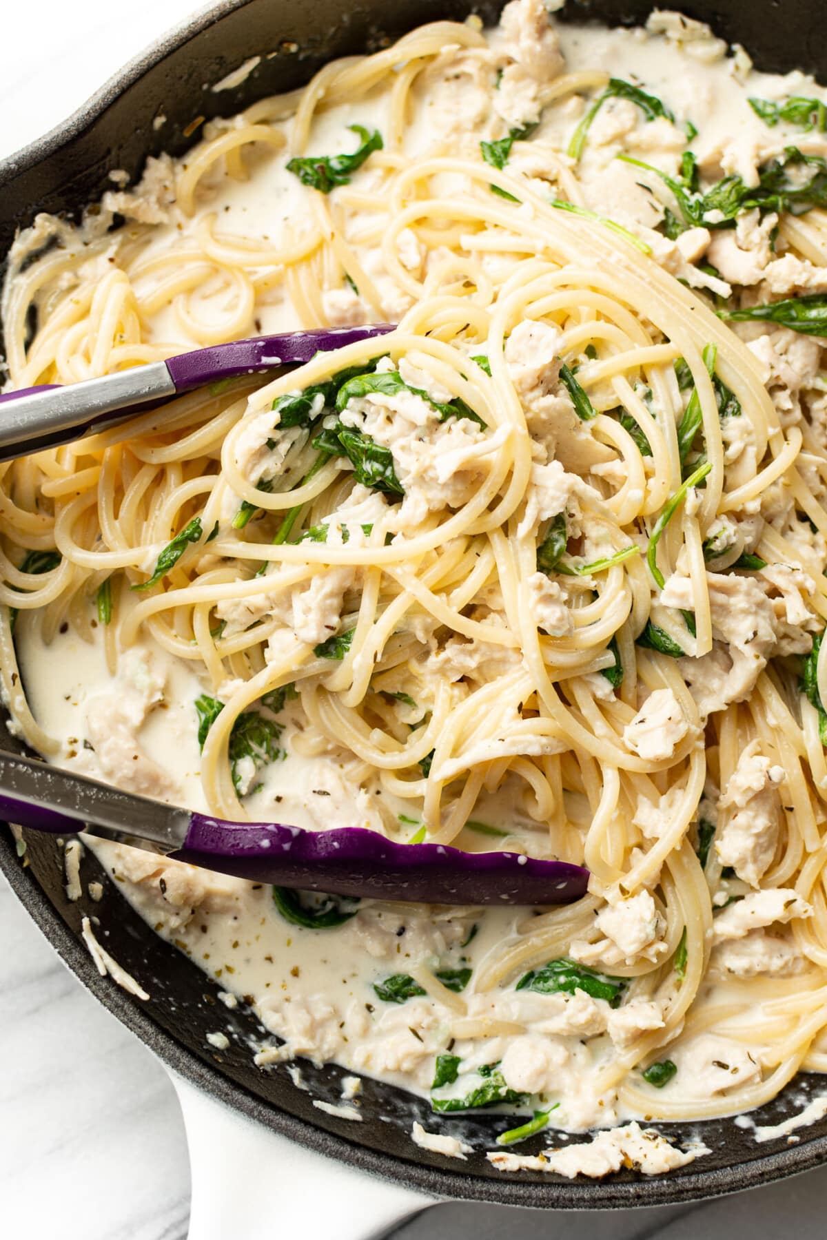 tossing lemon spinach chicken pasta in a skillet