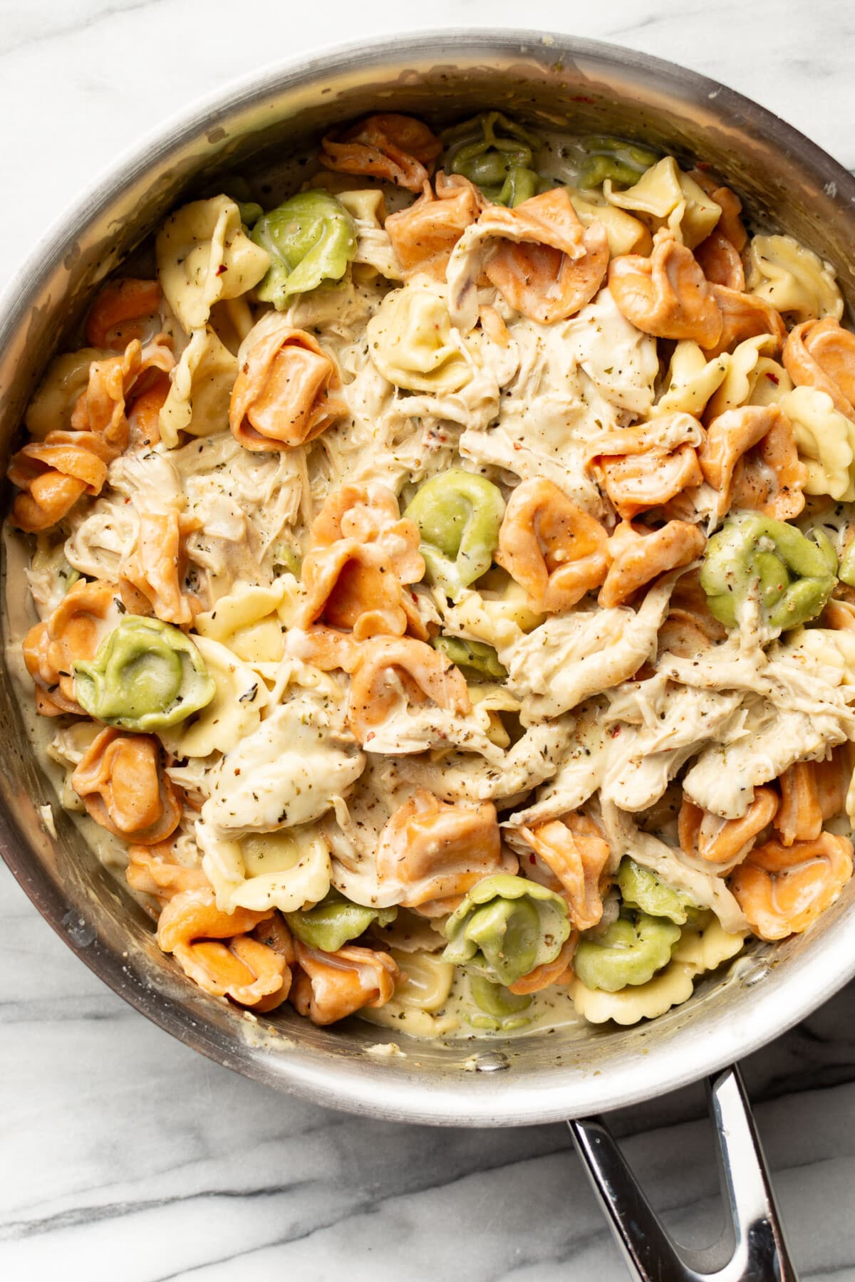 a skillet with creamy pesto chicken tortellini