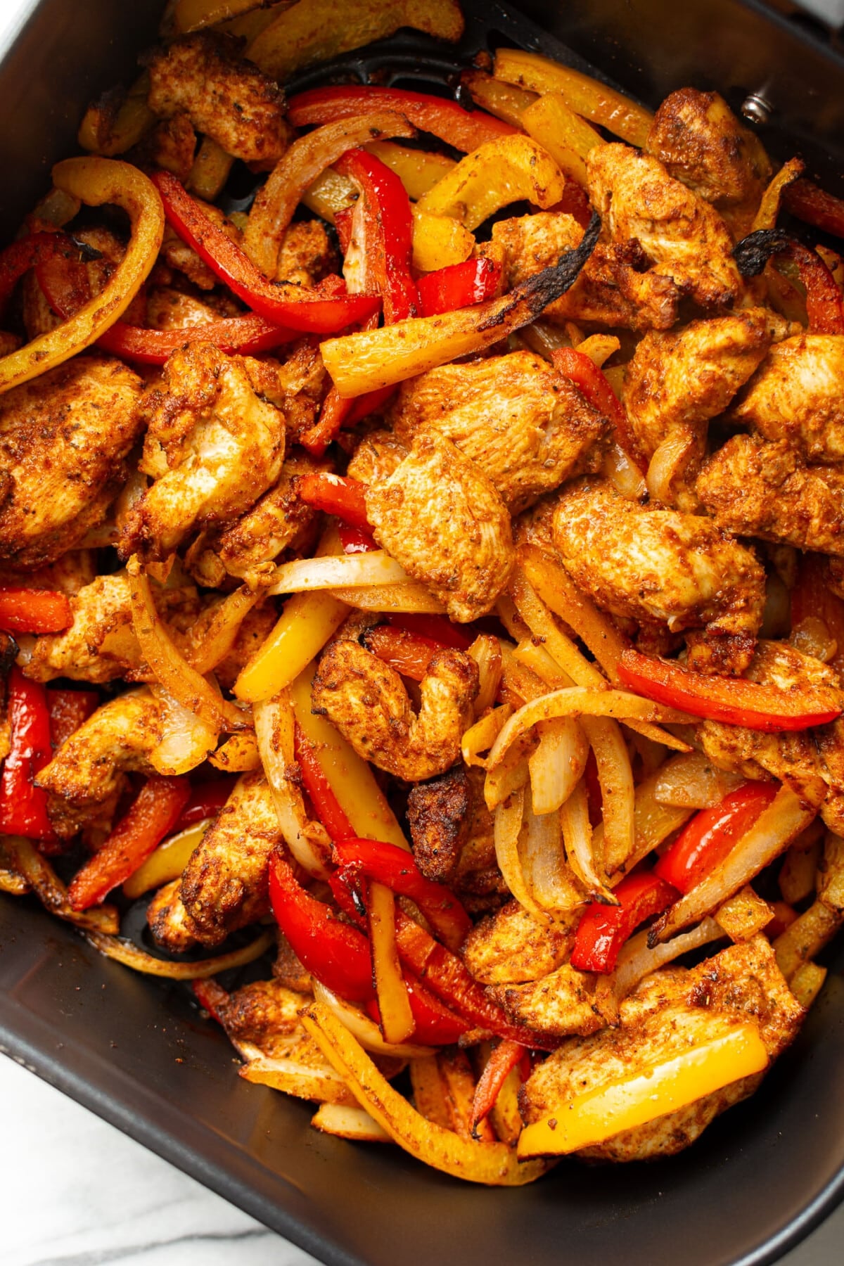 an air fryer basket with chicken fajitas