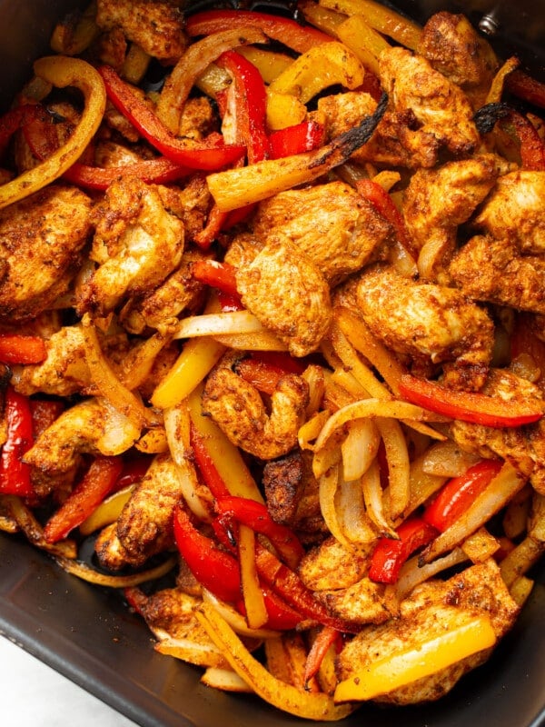 an air fryer basket with chicken fajitas