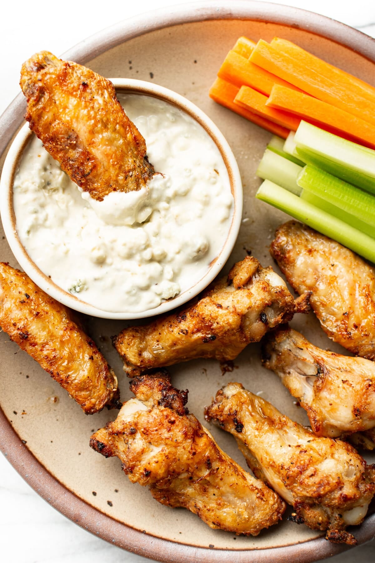 buffalo wings on a plate with homemade blue cheese dressing, carrots, and celery