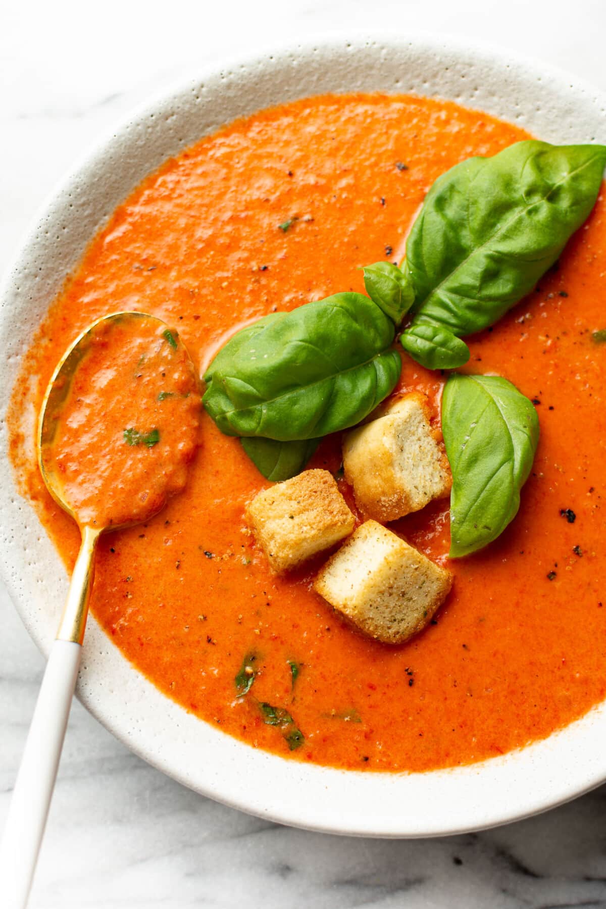a bowl of roasted red pepper soup with a spoon