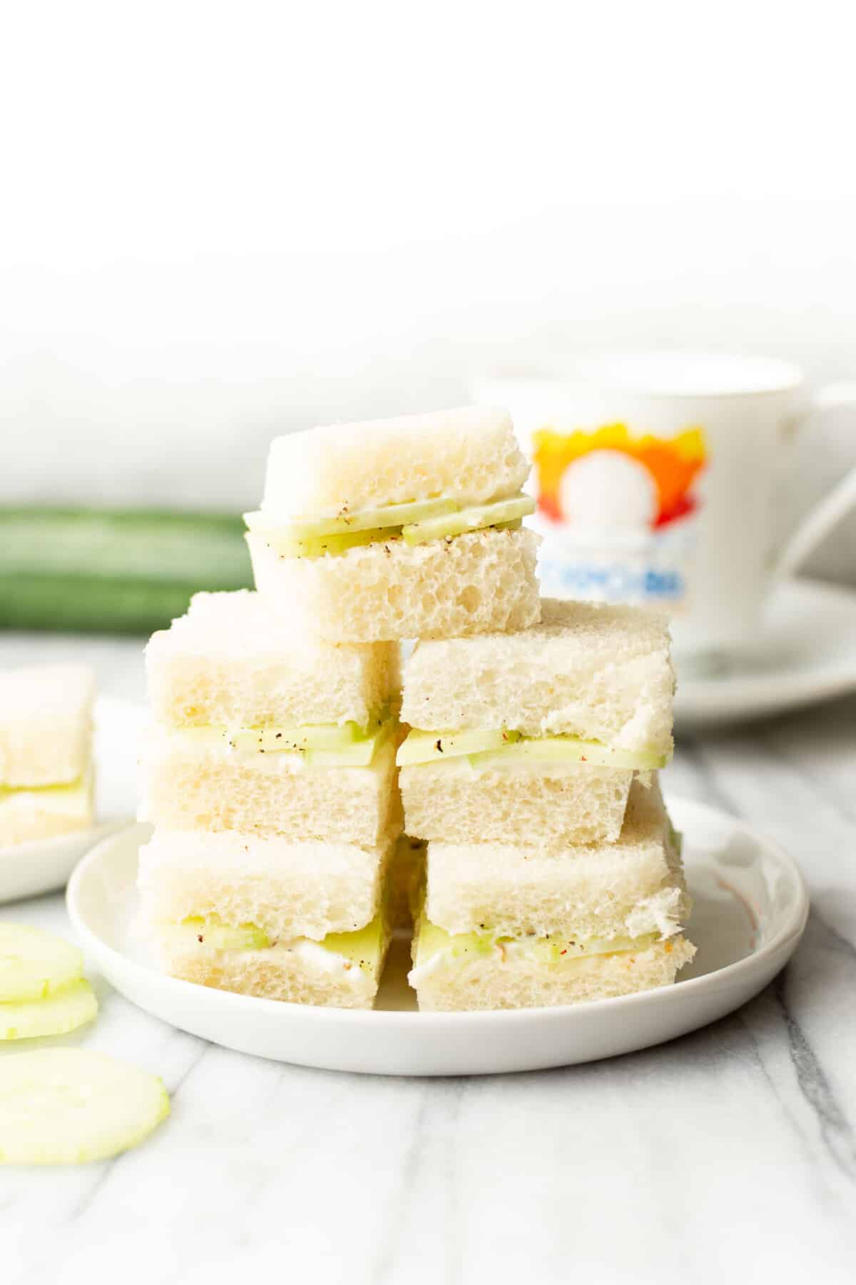 a plate with stacked cucumber sandwiches