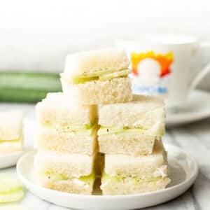 a plate with stacked cucumber sandwiches