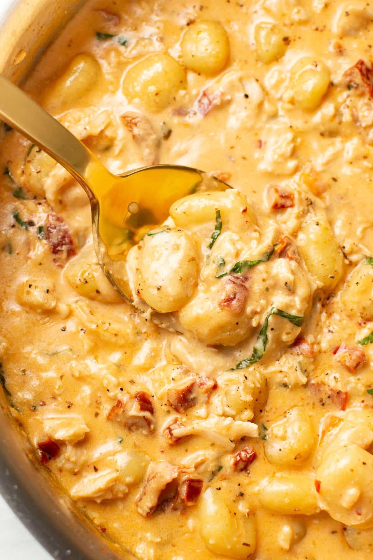 closeup of a skillet with marry me chicken gnocchi and a serving spoon