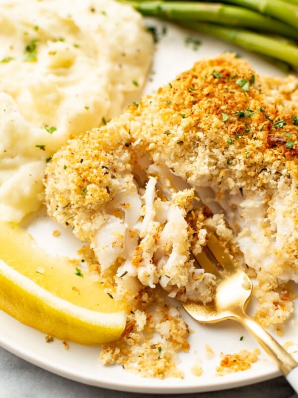 a plate with parmesan crusted cod, mashed potatoes, green beans, and a fork